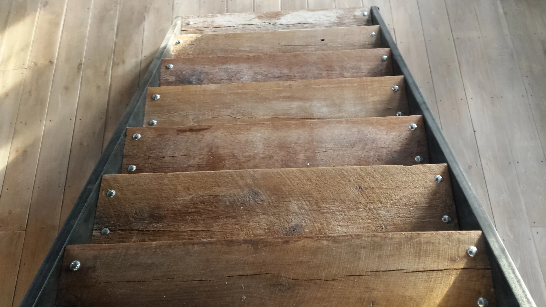 Original barn floor joists cut and fitted as stair treads in the channel-iron stringers